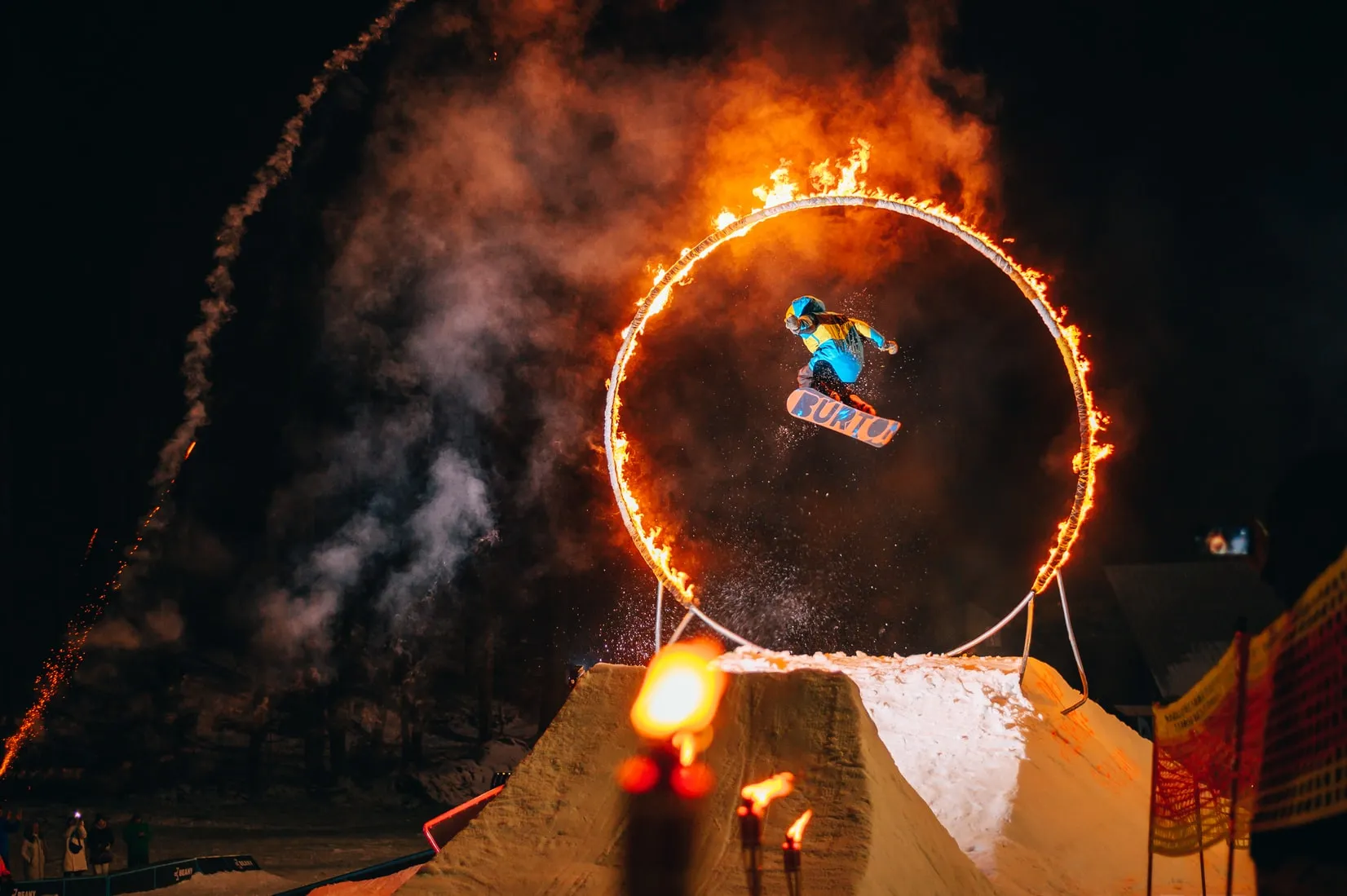 Culture Places to Visit - travelers watch a fire show in which a snowboarder jumps into a ring of fire