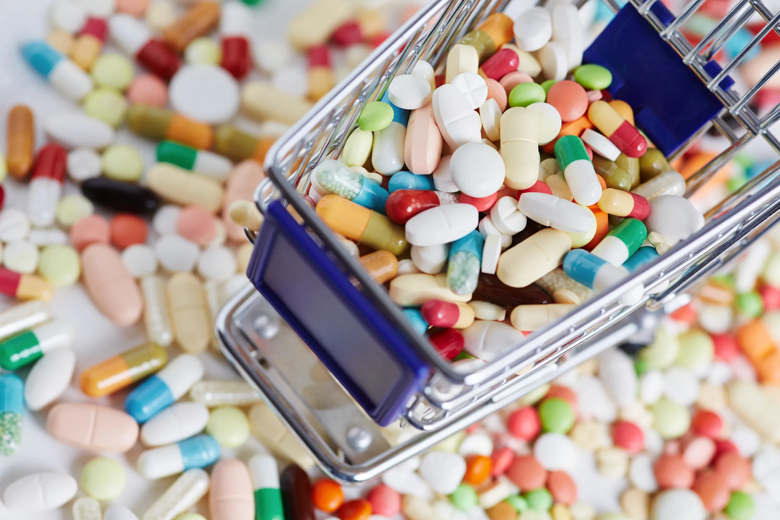 A shopping cart overflowing with various cororfull pills and capsules