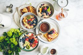 Several plates with a beautiful tourist breakfast - porridge, waffles, sauces, honey